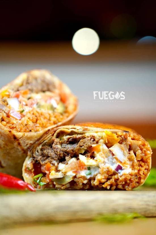 A loaded burrito sliced open to reveal beef, Mexican rice, beans and melted cheese